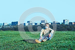 Medical mask as protection against coronavirus. guy sits in a clearing away from the city hiding from the coronavirus