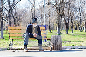 Medical mask as protection against coronavirus. the guy is sitting alone on a bench. not a single person is around