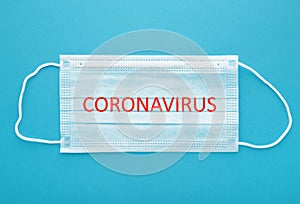 Medical mask on a blue background with copy space. The inscription Coronavirus