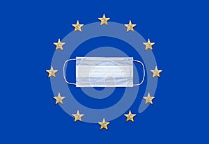 Medical mask on blue background flat lay top view copy space. Flag of the European Union. Protection against virus, coronavirus,