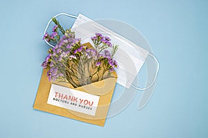 Medical mask, a bouquet of spring wildflowers in an envelope and the inscription Thank you to the doctor and nurses