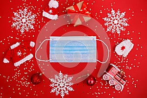 Medical mask, christmas decorations on red background with stars confetti. Medical protection covid-19 virus concept. New Year`s