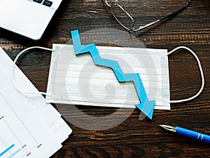 Medical mask and down arrow as symbol of decrease of economy or number of cases per covid-19.