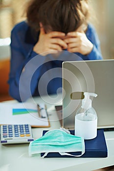 Medical mask and hand disinfectant and stressed woman