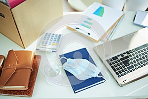 Medical mask and hand disinfectant on table in home office