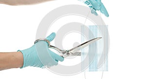 Medical mask in hands in a blue disposable blue medical glove cut with scissors a blue mask on a white background. The concept of