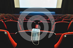 A medical mask hangs on a chair in an empty cinema hall. Pandemic and crisis in the industry. Delayed movie premieres