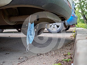 A medical mask hangs on the exhaust pipe of a car