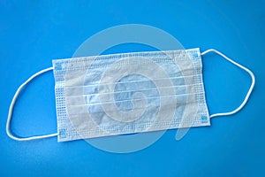 medical mask lies on a blue background, hygiene products protection from covid