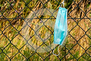 Medical mask on mesh wire fence