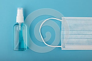 Medical mask and sanitizer on a blue background. Antiseptic and protective disposable mask on blue background. Hygiene
