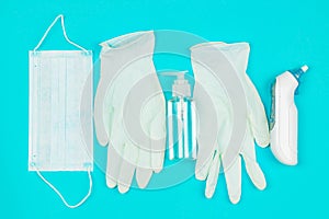 Medical mask, thermometer, white latex gloves and hand sanitizer gel on blue background.
