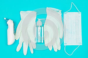 Medical mask, thermometer, white latex gloves and hand sanitizer gel on blue background.