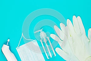 Medical mask, thermometer, white latex gloves and hand sanitizer gel on blue background.