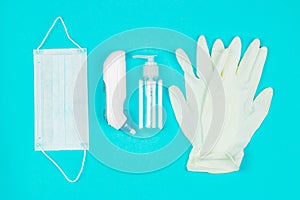 Medical mask, thermometer, white latex gloves and hand sanitizer gel on blue background