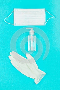 Medical mask, white latex gloves and hand sanitizer gel on blue background.