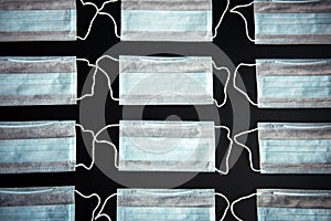 Medical masks in rows isolated on black. Blue surgical face masks on the table, close-up. Medical background. Concept of