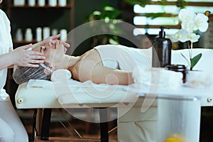 medical massage therapist in spa salon massaging clients face