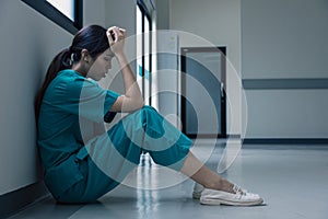 Medical nurse is sitting down on floor in frustration and grief after failure of patient body condition