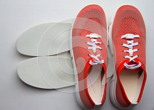 Medical orthopedic insoles with sport shoes isolated on a neutral background. Top view