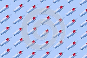 Medical pattern with plastic syringes of red vaccine.