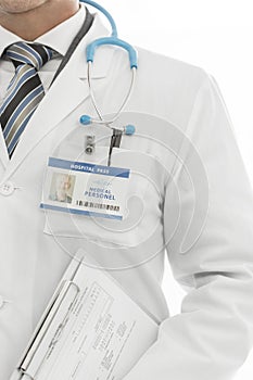 Midsection of doctor in labcoat with identity card holding clipboard at clinic photo