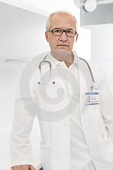 Portrait of confident senior doctor in labcoat standing at hospital photo
