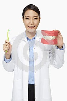 Medical personnel holding up a tooth brush and a set of dentures