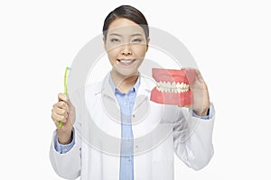 Medical personnel holding up a tooth brush and a set of dentures