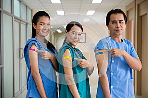 Medical personnel pointing to bandage with plaster on arm after getting against Covid-19 vaccine
