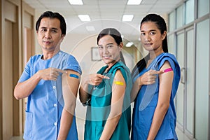 Medical personnel pointing to bandage with plaster on arm after getting against Covid-19 vaccine