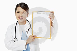 Medical personnel smiling and holding up a blank clipboard