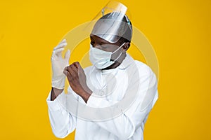 Medical personnel wearing lab coat, face mask and shield, adjusting his surgical gloves