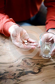 Medical pill on the wrinkly hand of an old man