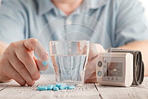 Medical pills against hypertension in hand, equipment for measuring blood pressure photo