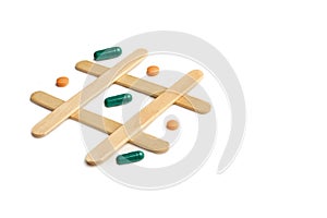 Medical pills and capsules in a tic tac toe game on white background