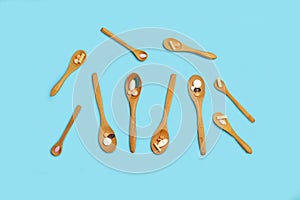 Medical pills and capsules on wooden spoons on a light blue background