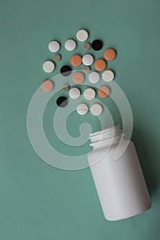 Medical pills of different colors and a white plastic bottle. Blue pastel background. Medicines. Close-up. Copy space.