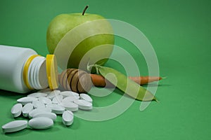 Medical pills spilling out of bottle on green