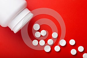 Medical pills spilling out of bottle. On red background. Top vie