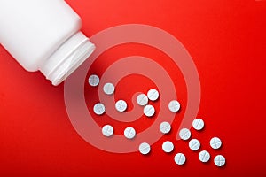 Medical pills spilling out of bottle. On red background. Top vie