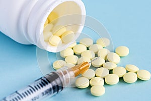 Medical pills and tablets spilling out of a drug bottle with syringe