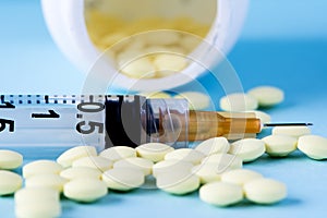 Medical pills and tablets spilling out of a drug bottle with syringe