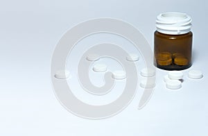 Medical pills and tablets spilling out of a drug bottle on the white background with copy space for text, health care