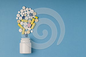 Medical pills and tablets spilling out of a white drug bottle. Copy space for text. Closeup, healthcare