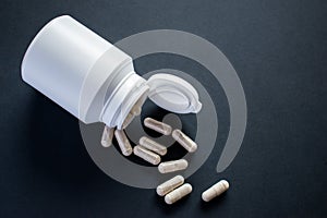 Medical pills, tablets with white pill bottle on black background