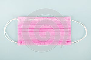 Medical pink face mask on a light blue background.Top view.Concept of protection against pandemic, viruses,epidemic,coronavirus.