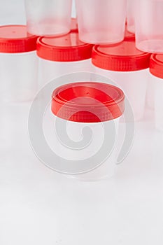 Medical plastic container for the collection of tests on the background of other containers, exhibited in two tiers