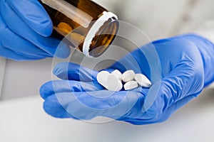 Medical practitioner wearing blue surgical latex gloves holding medicine bottle