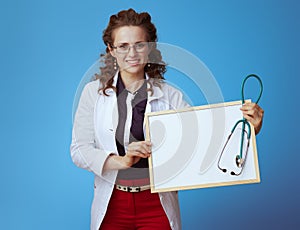 Medical practitioner woman showing blank board and stethoscope